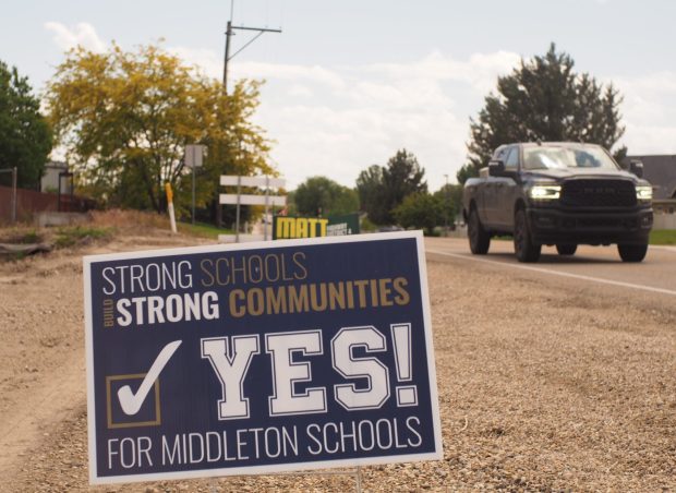 A truck drives past a campaign sign urging Middleton residents to vote in favor of a Middleton school district levy. The sign states, "Strong schools build strong communities."
