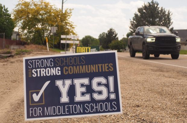 A truck drives past a campaign sign urging Middleton residents to vote in favor of a Middleton school district levy. The sign states, "Strong schools build strong communities."
