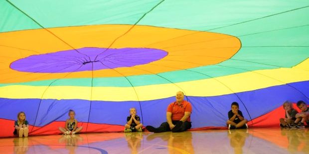 Moscow Superintendent Shawn Tiegs laughs while playing in a giant parachute with students during the first day of school on Wednesday, Aug. 27, 2025, in Moscow, Id.